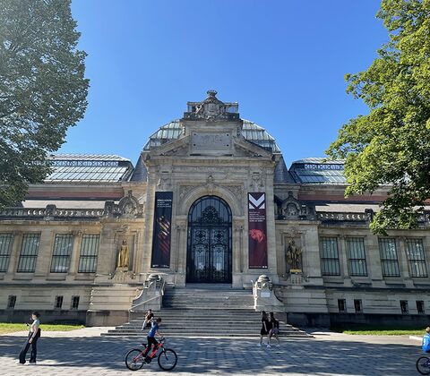 Façade du musée, par beau temps, avec passants.