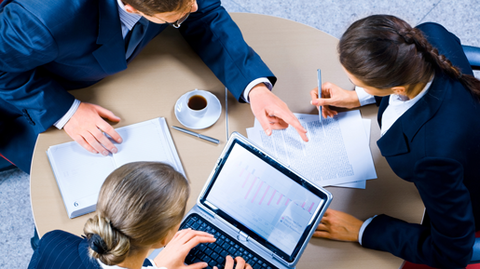 3 personnes travaillant sur ordinateur sur une table ronde